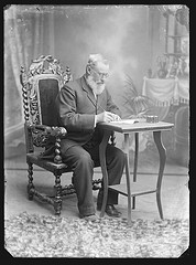 Seated portrait of a man with a beard writing a document.